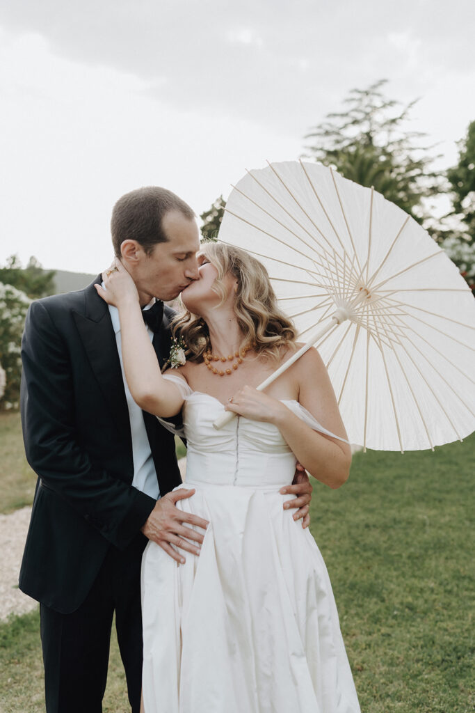 Bride-and-groom-kissing-under-parasol-romantic-moment-soft-light-wedding-in-provence-chateau-de-robernier